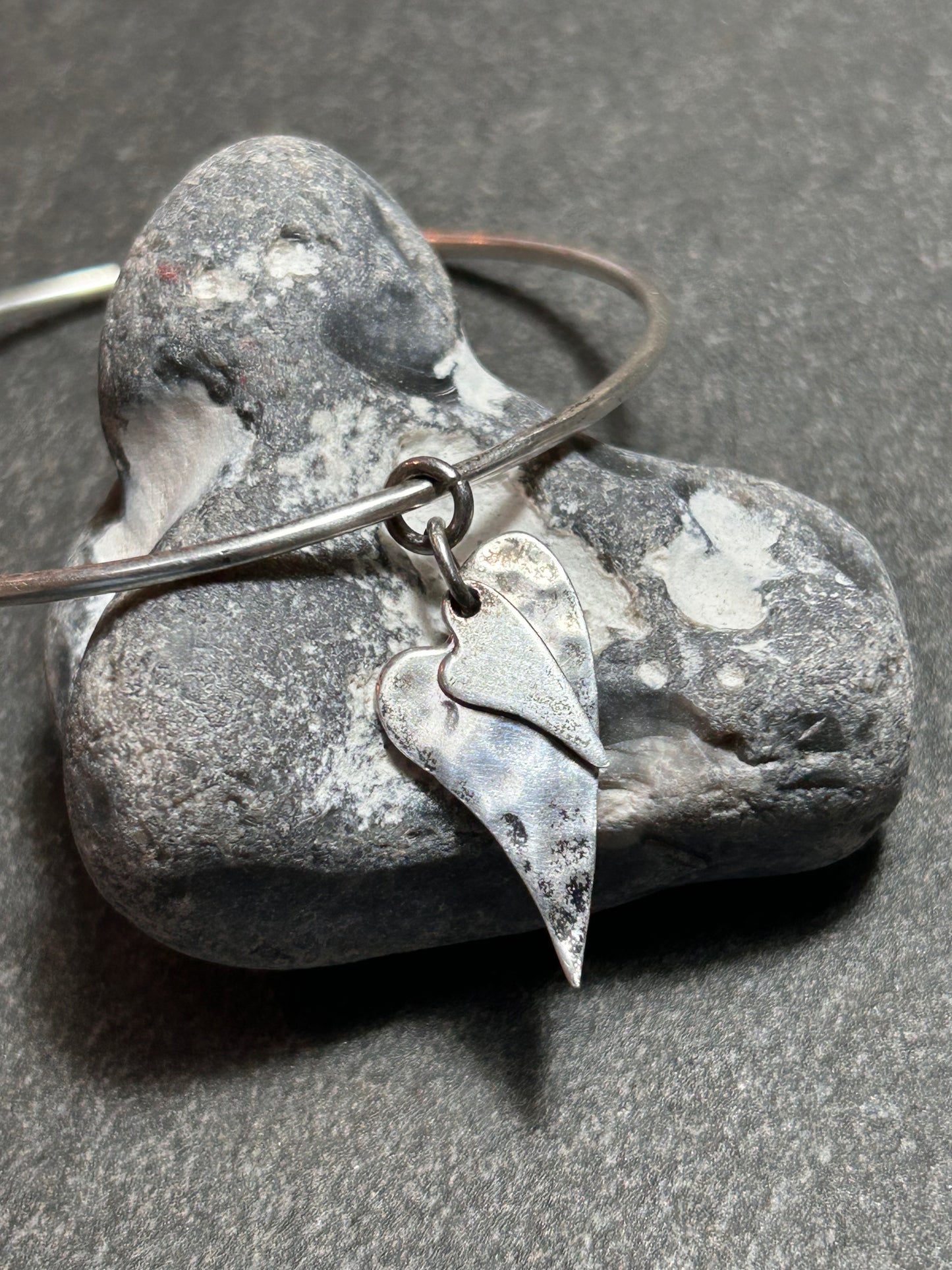 Delicate artisan bangle with two silver hearts.