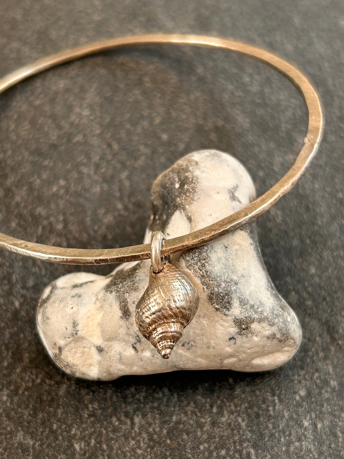 Delicate artisan sterling silver bangle with shell charm.
