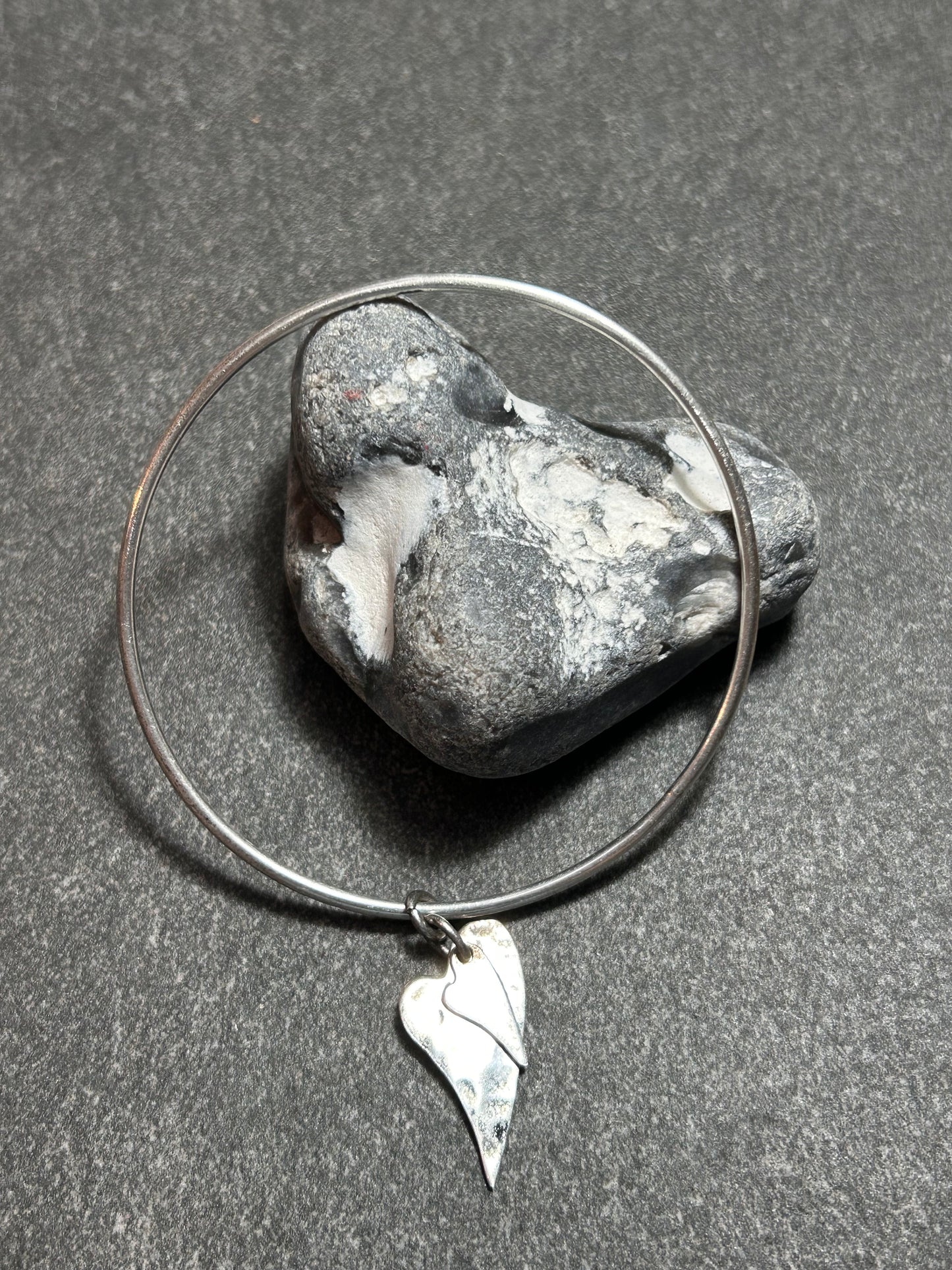 Delicate artisan bangle with two silver hearts.