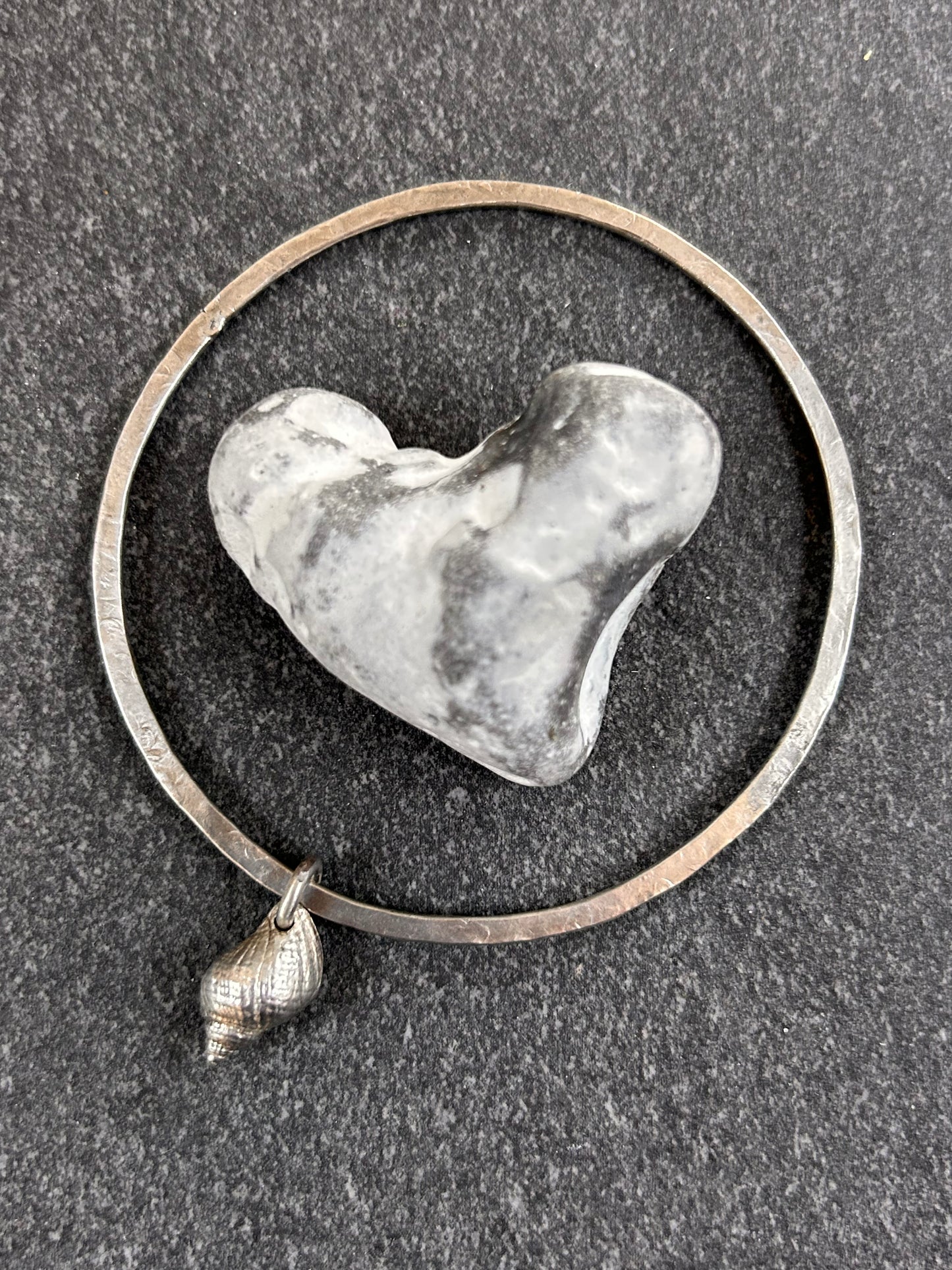 Delicate artisan sterling silver bangle with shell charm.
