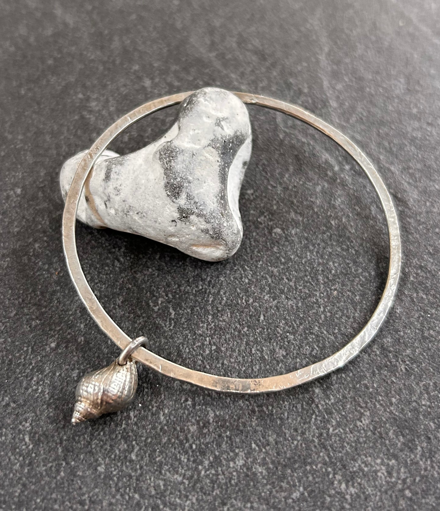 Delicate artisan sterling silver bangle with shell charm.