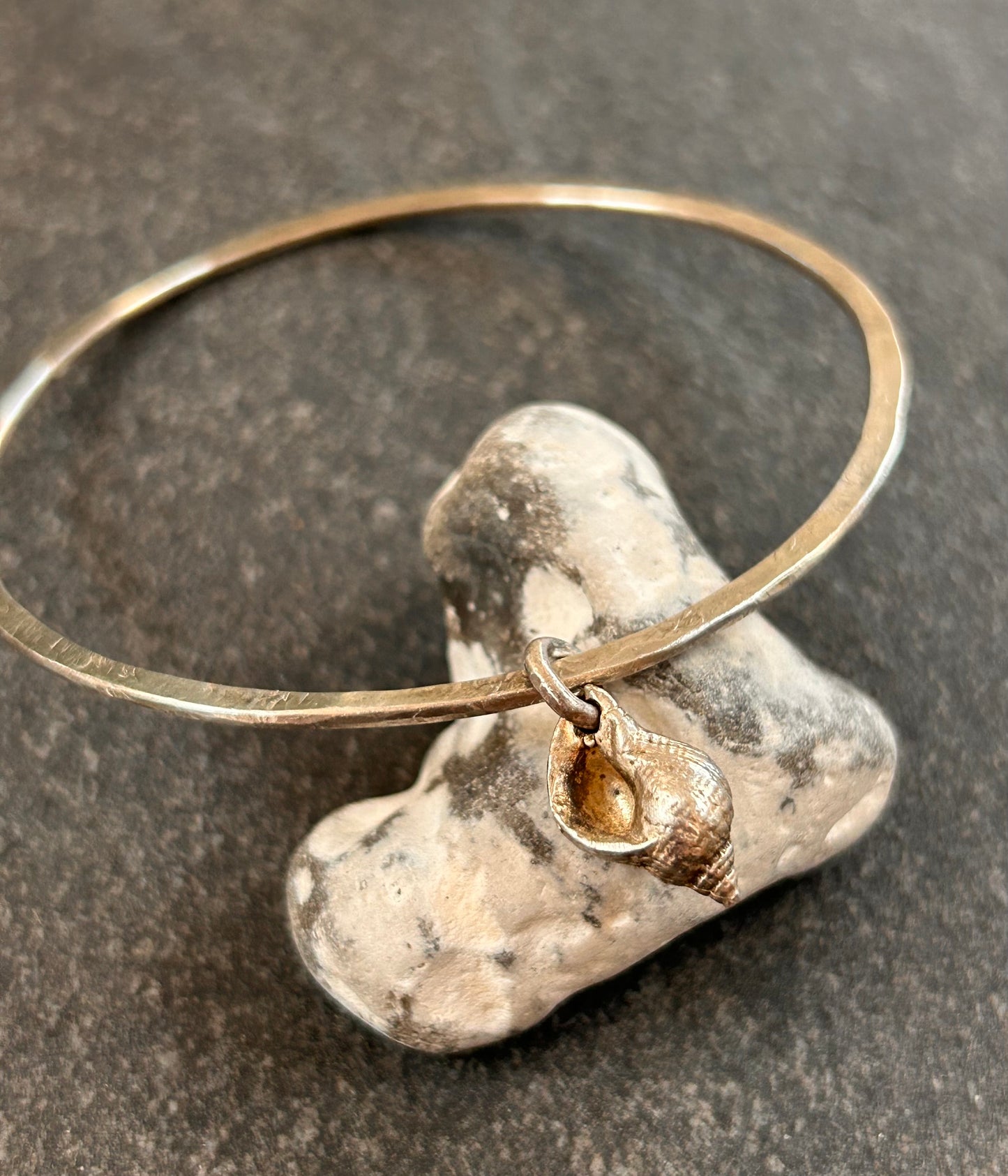 Delicate artisan sterling silver bangle with shell charm.