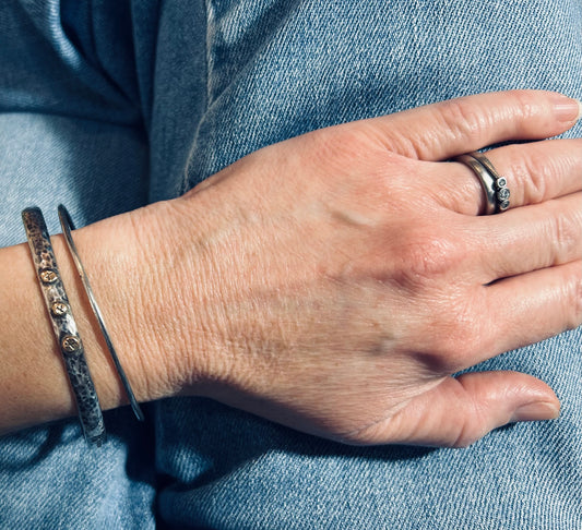 Delicate artisan bangle with two silver hearts.