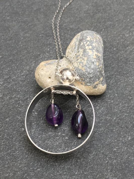 Unusual vintage circular sterling silver pendant with two amethyst drops suspended on a moving sterling silver chain.